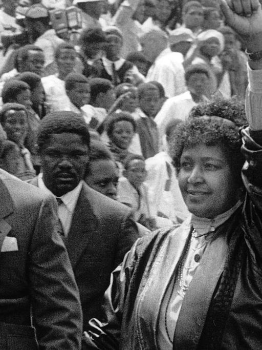 Nelson Mandela und seine Frau Winnie laufen durch eine Menschenmenge und heben ihre Fäuste.