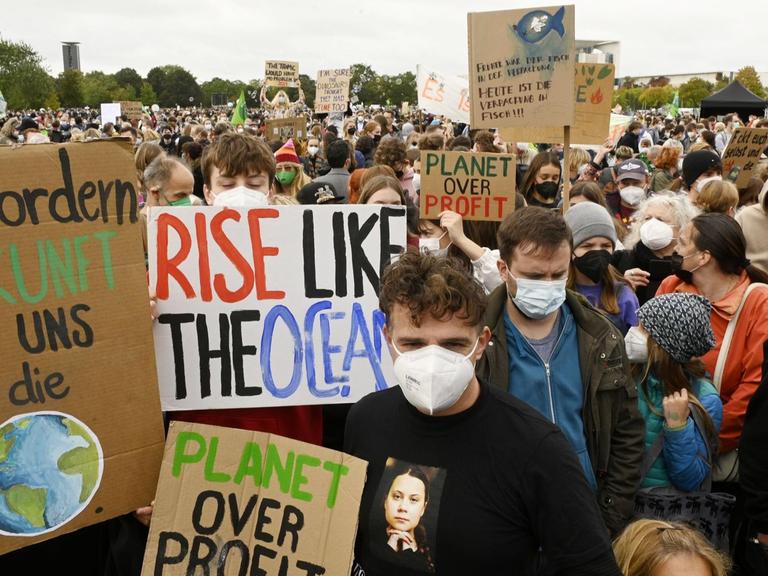 Demonstrierende beim globalen Klimastreik von Fridays for Future in Berlin. Sie halten Transparente mit Sprüchen wie "Planet over profit".