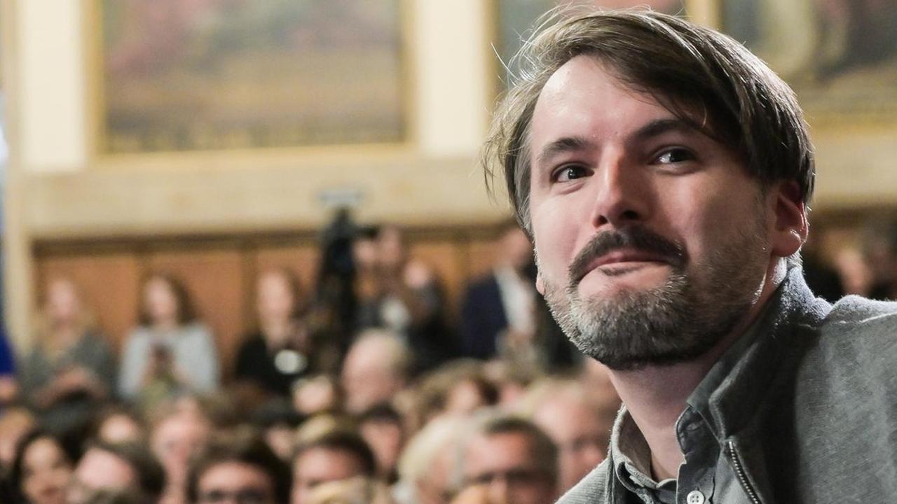 Der Schriftsteller Saša Stanišić erhebt sich, um den Deutschen Buchpreis entgegen zu nehmen Der Schriftsteller Saša Stanišić erhebt sich, um den Deutschen Buchpreis entgegen zu nehmen