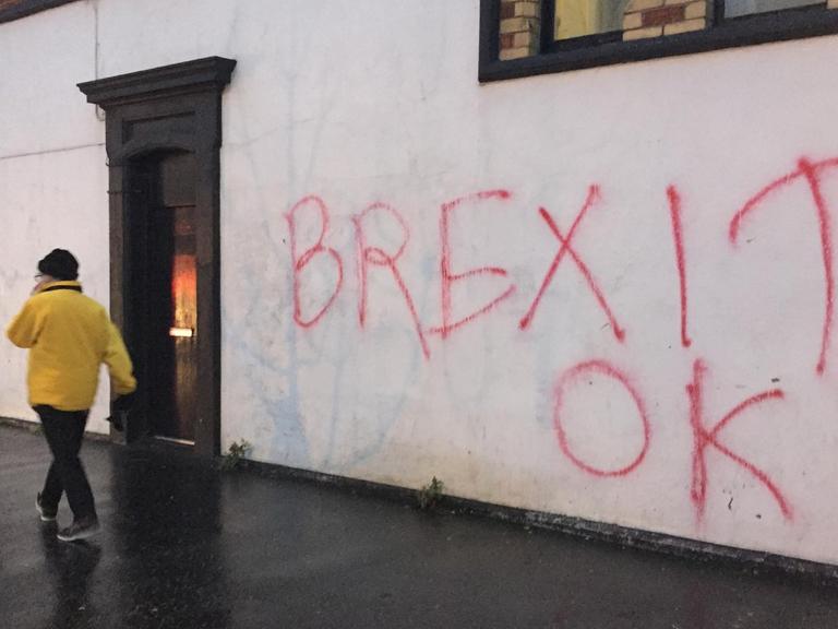 Ein Mann geht an einem Brexit-Graffiti in Belfast vorbei.