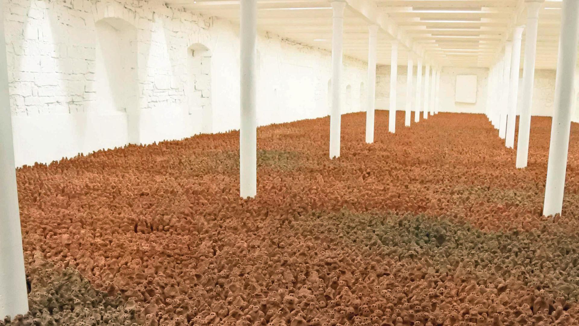 Kunstwerk "European Field" des britischen Künstlers Antony Gormley von 1993: eine Masse von Terracotta-Figuren steht auf dem Boden eines großen Raums mit weißen Wänden und weißen Säulen. Kunstwerk "European Field" des britischen Künstlers Antony Gormley von 1993: eine Masse von Terracotta-Figuren steht auf dem Boden eines großen Raums mit weißen Wänden und weißen Säulen.