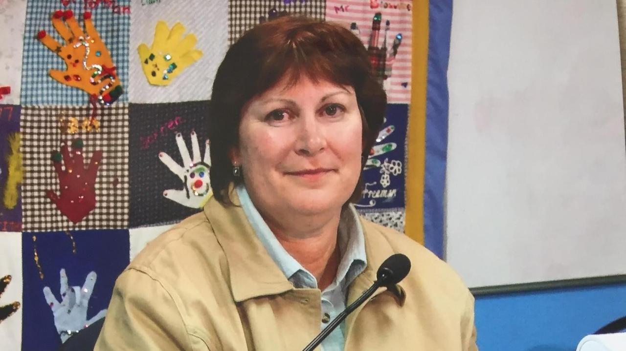 Eine Frau mit mittellangen glatten dunklen Haaren sitzt mit Jacket und Bluse vor einem Bildschirm und einem Mikrofon. Eine Frau mit mittellangen glatten dunklen Haaren sitzt mit Jacket und Bluse vor einem Bildschirm und einem Mikrofon.