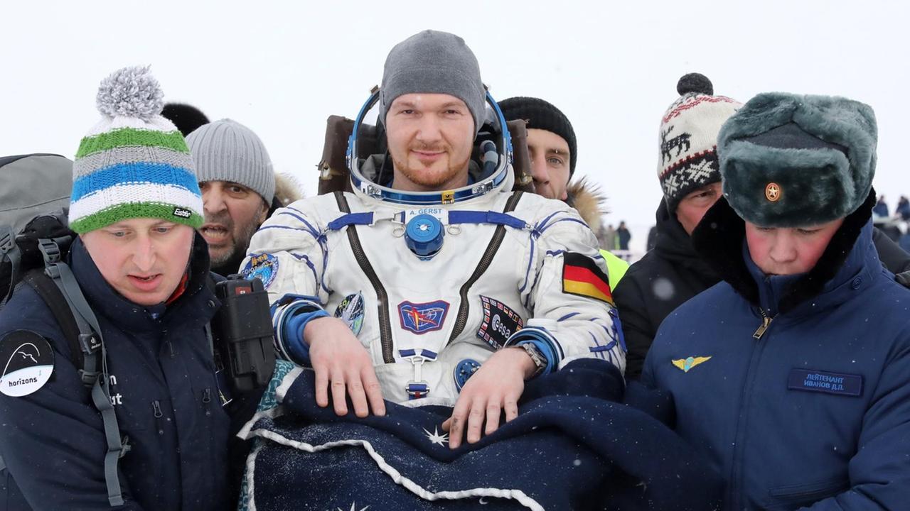 20.12.2018, Kasachstan: KAZAKHSTAN - DECEMBER 20, 2018: ESA Astronaut Alexander Gerst bei der Sojuz MS-09 Landungskapsel in Kasachstan am 20.12.2018, getragen von zwei Landungshelfern. 20.12.2018, Kasachstan: KAZAKHSTAN - DECEMBER 20, 2018: ESA Astronaut Alexander Gerst bei der Sojuz MS-09 Landungskapsel in Kasachstan am 20.12.2018, getragen von zwei Landungshelfern.