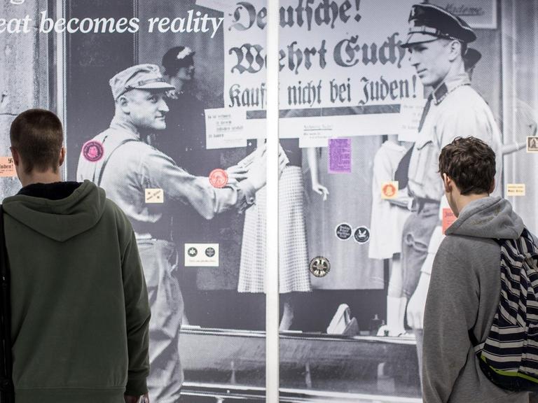 Jugendliche betrachten eine Wand mit verschiedenen antisemitischen Klebezetteln am 2017 im NS-Dokumentationszentrum in München