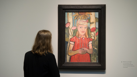 Eine Frau betrachtet das Werk "Mädchen in rotem Kleid vor Sonnenblume" (1907) von Paula Modersohn-Becker im Bucerius Kunstforum in Hamburg.