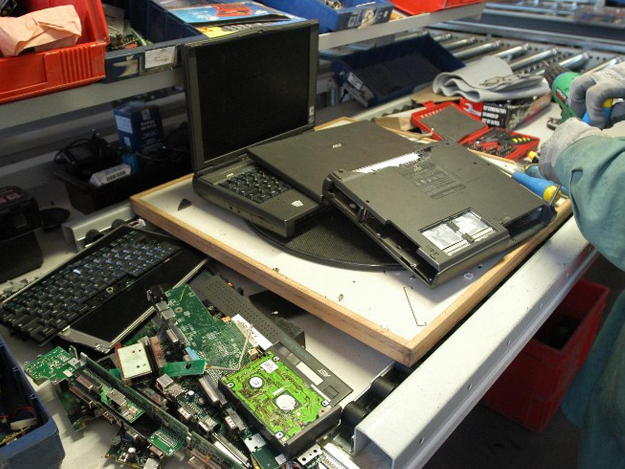 Ein Arbeiter entnimmt einem Laptop Wertstoffe wie Edelmetalle zur Wiederverwertung. 
