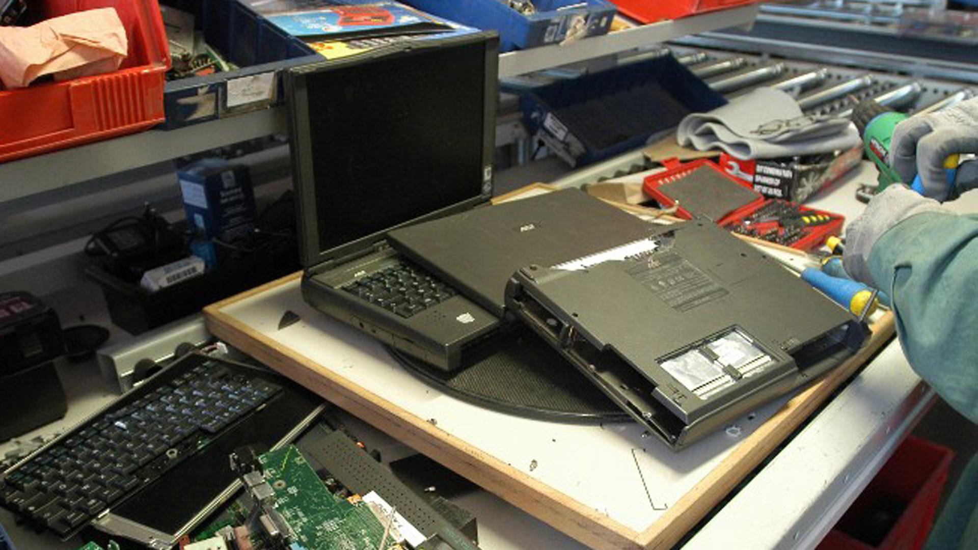 Ein Arbeiter entnimmt einem Laptop Wertstoffe wie Edelmetalle zur Wiederverwertung. Ein Arbeiter entnimmt einem Laptop Wertstoffe wie Edelmetalle zur Wiederverwertung.