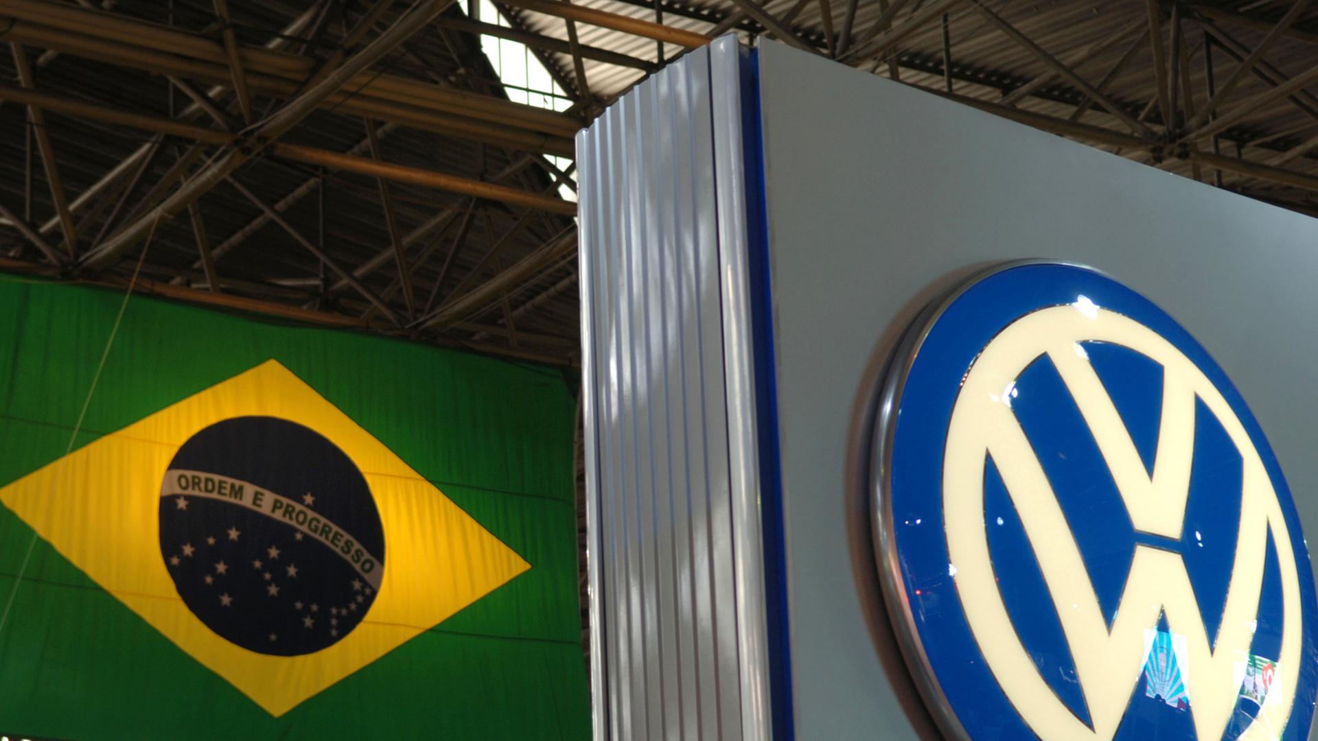 Das Logo von Volkswagen vor der Flagge von Brasilien Das Logo von Volkswagen vor der Flagge von Brasilien