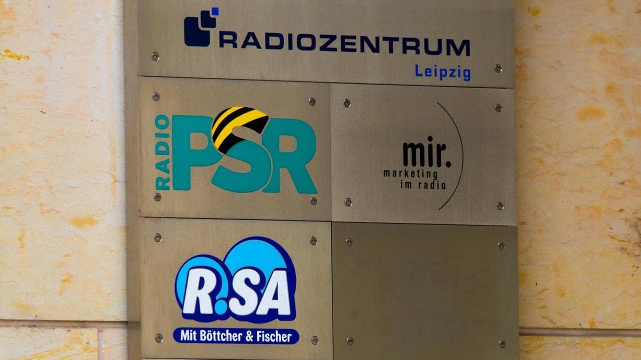 Auf einem Schild sind die Namen mehrerer Radiosender zu lesen.