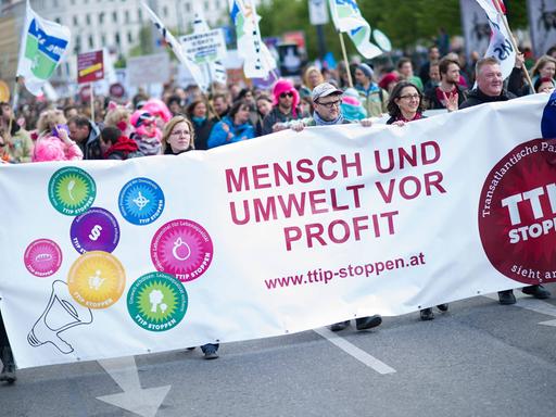 Menschen demonstrieren in Wien gegen das TTIP-Abkommen. Sie halten ein Transparent mit der Aufschrift "Mensch und Umwelt vor Profit".