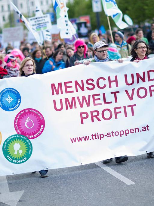 Menschen demonstrieren in Wien gegen das TTIP-Abkommen. Sie halten ein Transparent mit der Aufschrift "Mensch und Umwelt vor Profit".