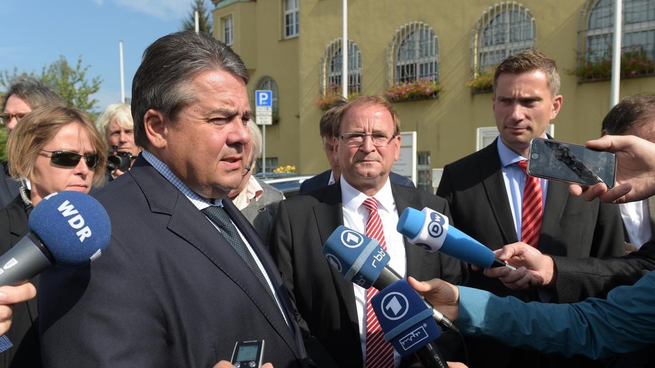 Gabriel, Opitz und der sächsische Wirtschaftsminister Dulig sprechen in Mikrofone und sind von Journalisten umringt. Gabriel, Opitz und der sächsische Wirtschaftsminister Dulig sprechen in Mikrofone und sind von Journalisten umringt.