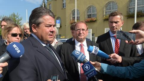 Gabriel, Opitz und der sächsische Wirtschaftsminister Dulig sprechen in Mikrofone und sind von Journalisten umringt.