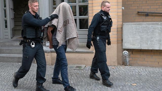 Polizisten in Berlin führen einen verdächtigen Mann nach einer Razzia gegen Mitglieder arabischer Großfamilien ab.