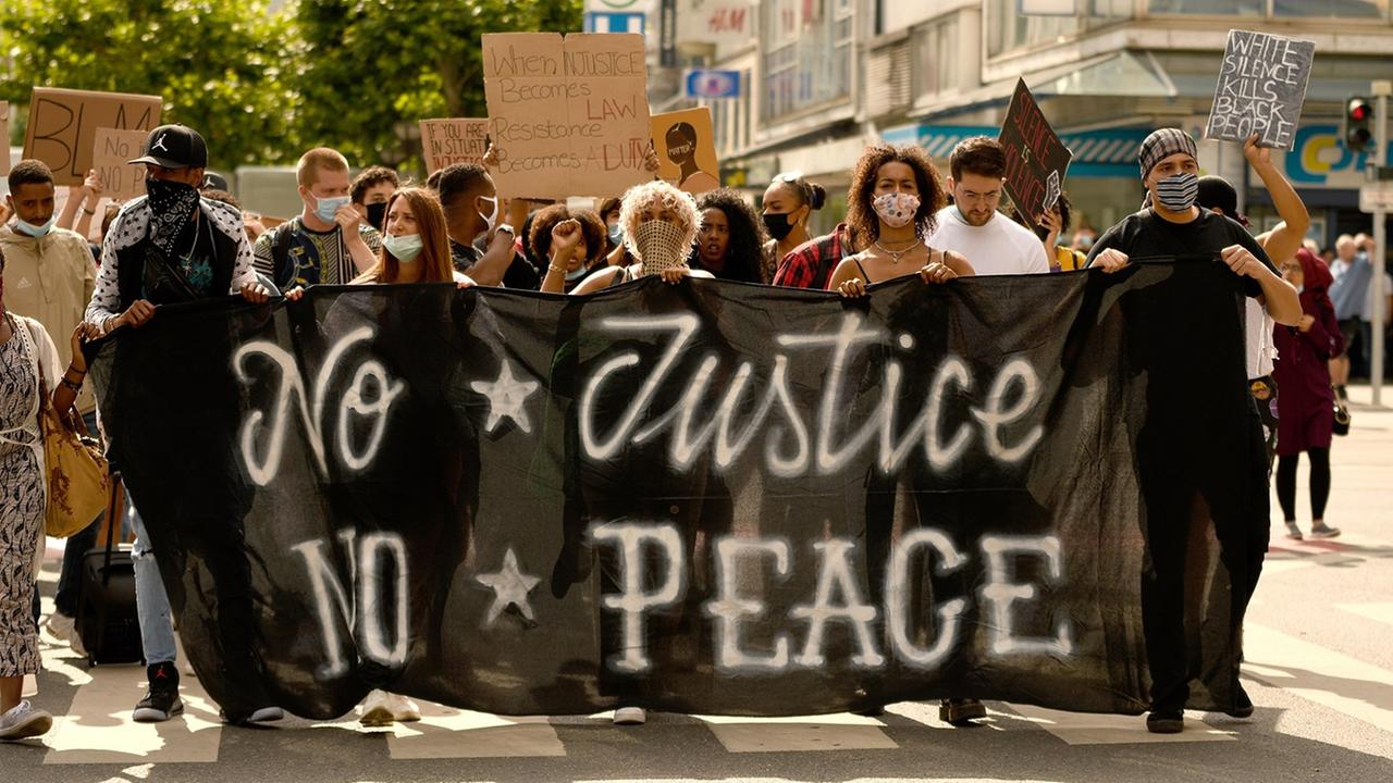 "Black Lives Matter"-Demonstranten laufen hinter einem Plakat mit der Aufschrift "No Justice, No Peace". "Black Lives Matter"-Demonstranten laufen hinter einem Plakat mit der Aufschrift "No Justice, No Peace".