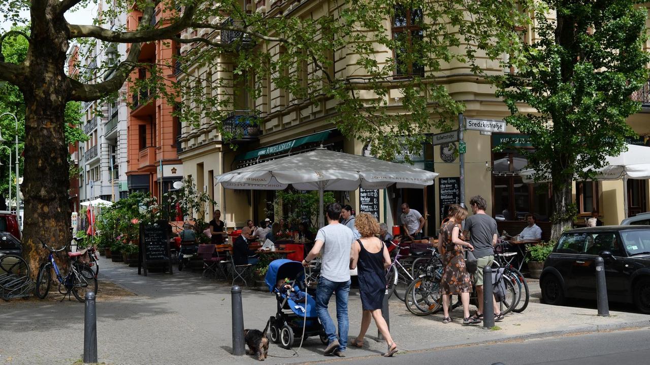 Passanten mit einem Kinderwagen laufen am Café SowohlAlsAuch in Berlin Prenzlauer Berg vorbei. Passanten mit einem Kinderwagen laufen am Café SowohlAlsAuch in Berlin Prenzlauer Berg vorbei.