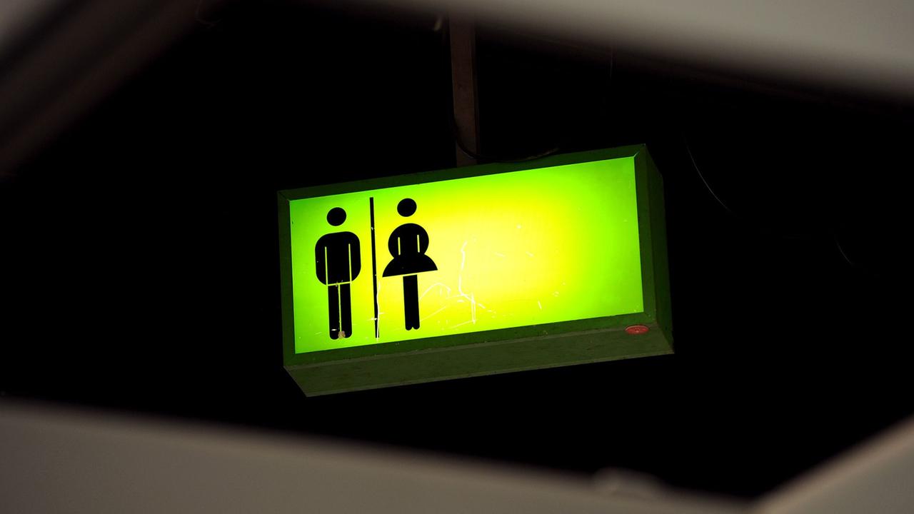 Ein grün leuchtendes Toiletten-Hinweisschild Ein grün leuchtendes Toiletten-Hinweisschild