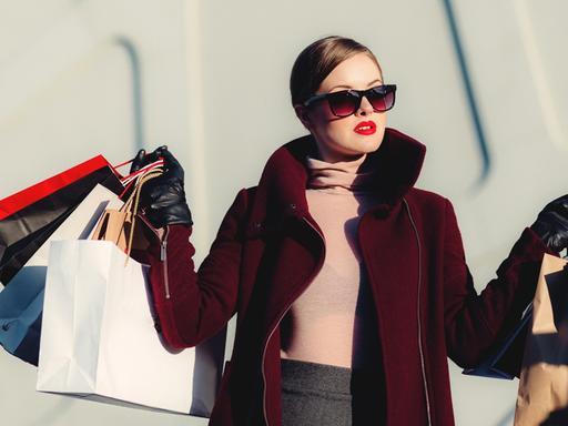 Eine elegante Frau trägt viele Shoppingtüten.