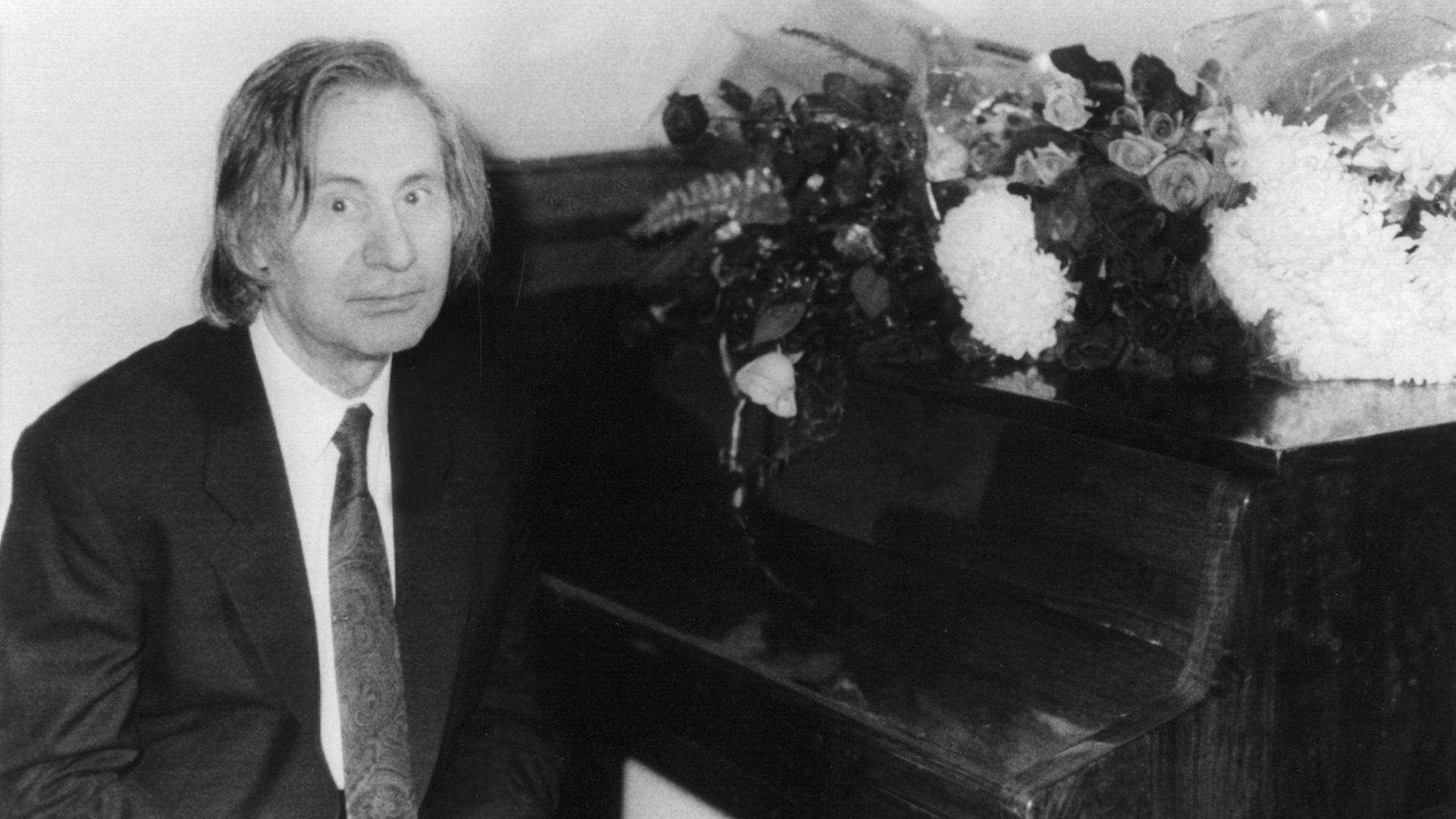 Der russische Komponist und Pianist Alfred Schnittke, schwarz-weiß-Aufnahme, an einem Klavier sitzend, in die Kamera blickend. Der russische Komponist und Pianist Alfred Schnittke, schwarz-weiß-Aufnahme, an einem Klavier sitzend, in die Kamera blickend.