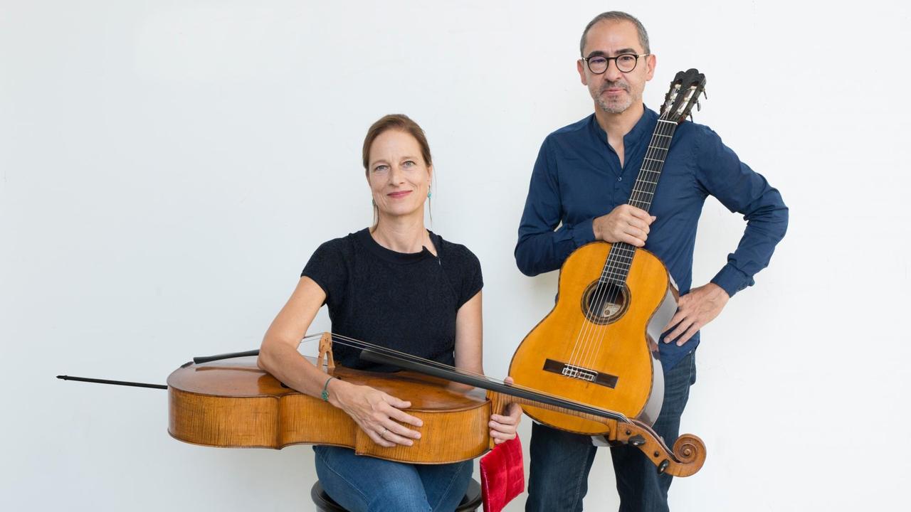 Anja Lechner hat ihr Cello sitzend quer auf dem Schoß liegen, neben ihr steht Pablo Márquez mit seiner Gitarre in der Hand. Anja Lechner hat ihr Cello sitzend quer auf dem Schoß liegen, neben ihr steht Pablo Márquez mit seiner Gitarre in der Hand.