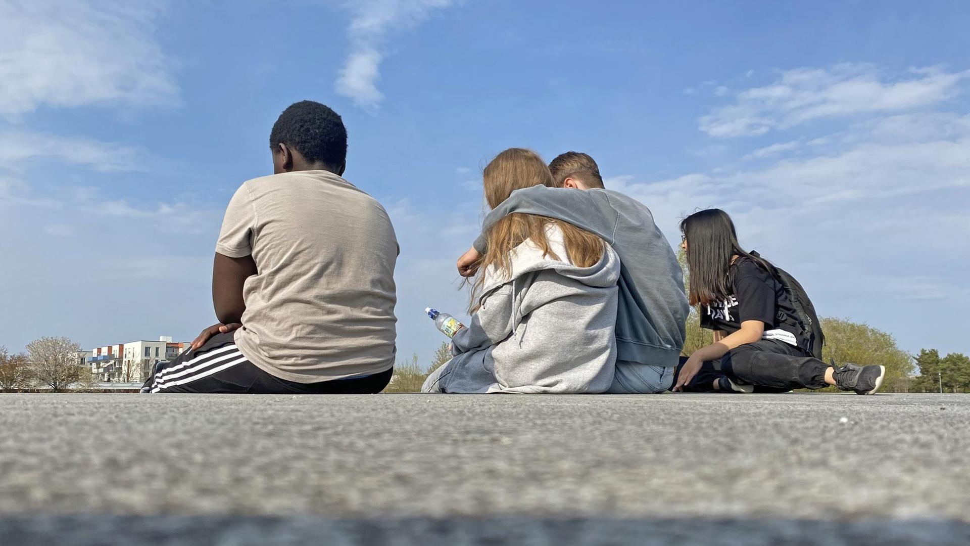 Vier Jugendliche sitzen auf einer Mauer im Riemer Park in München. Vier Jugendliche sitzen auf einer Mauer im Riemer Park in München.