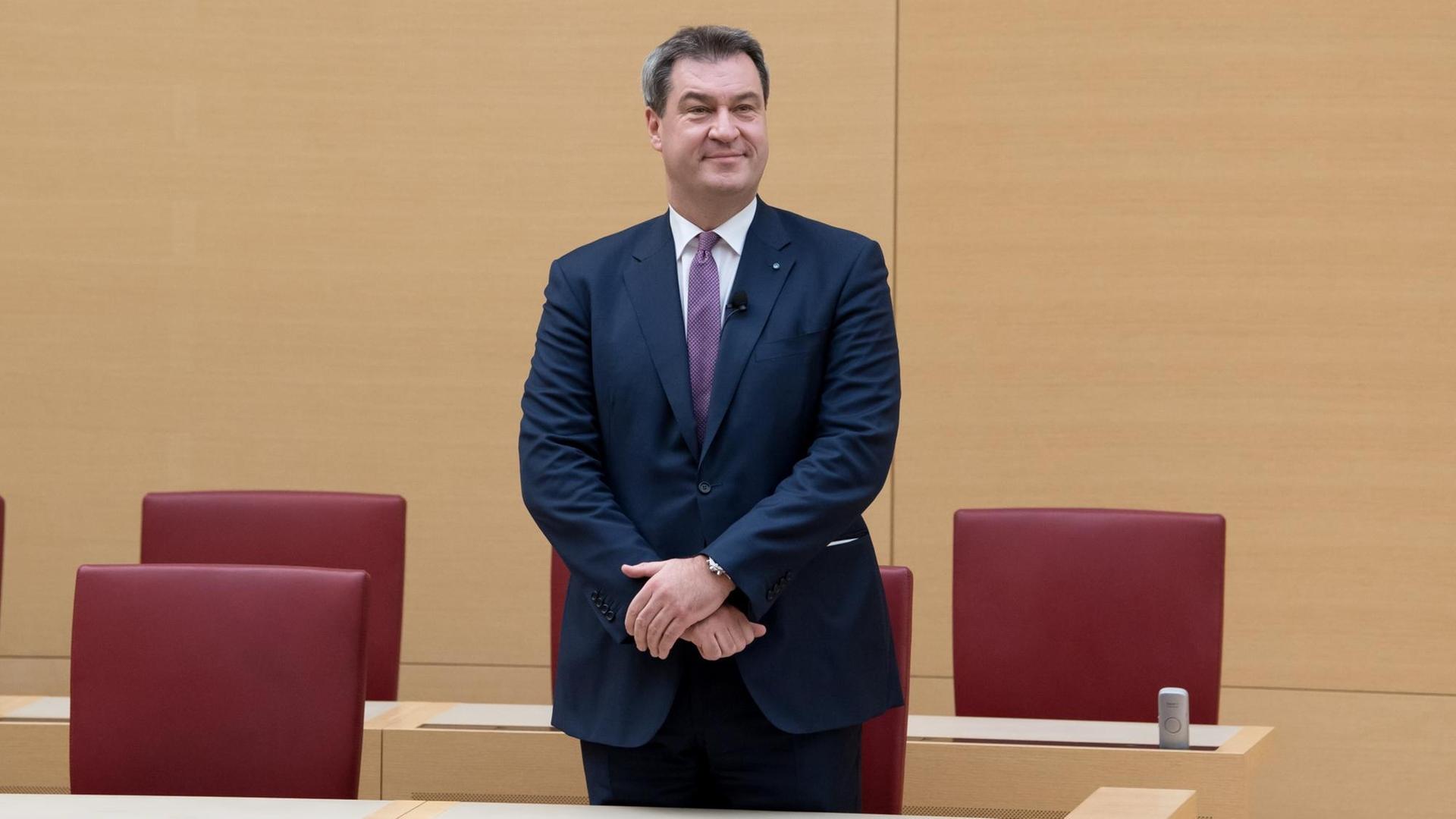 Söder steht an seinem Platz in der Regierungsbank im Landtag und schaut zufrieden. Söder steht an seinem Platz in der Regierungsbank im Landtag und schaut zufrieden.