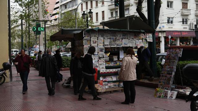 Leute an einem Zeitungsstand lesen Zeitungen in Athen.