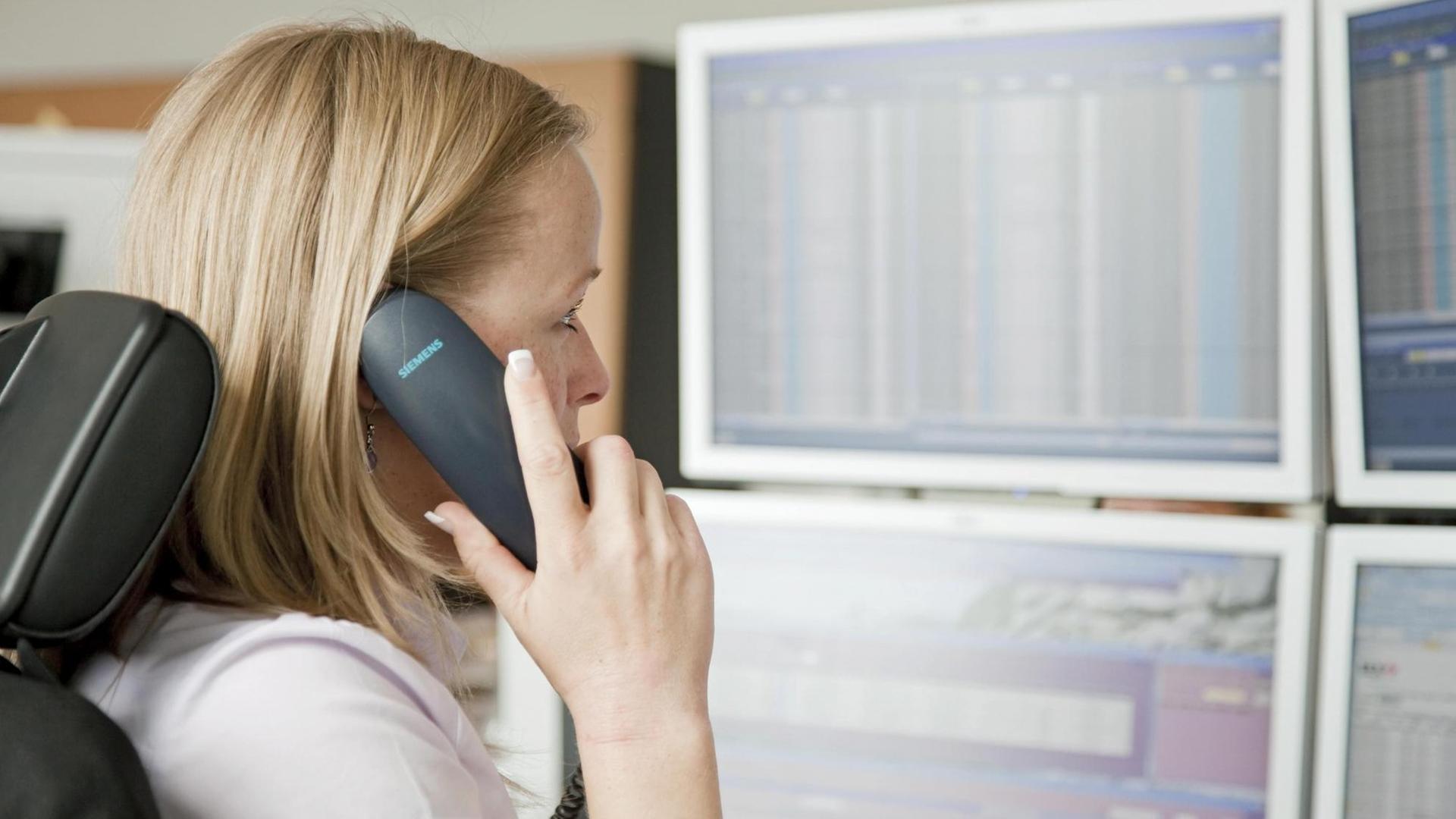 Eine Frau telefoniert vor Monitoren. Handelsraum der European Energy Exchange, EEX, Europäische Energiebörse. Eine Frau telefoniert vor Monitoren. Handelsraum der European Energy Exchange, EEX, Europäische Energiebörse.