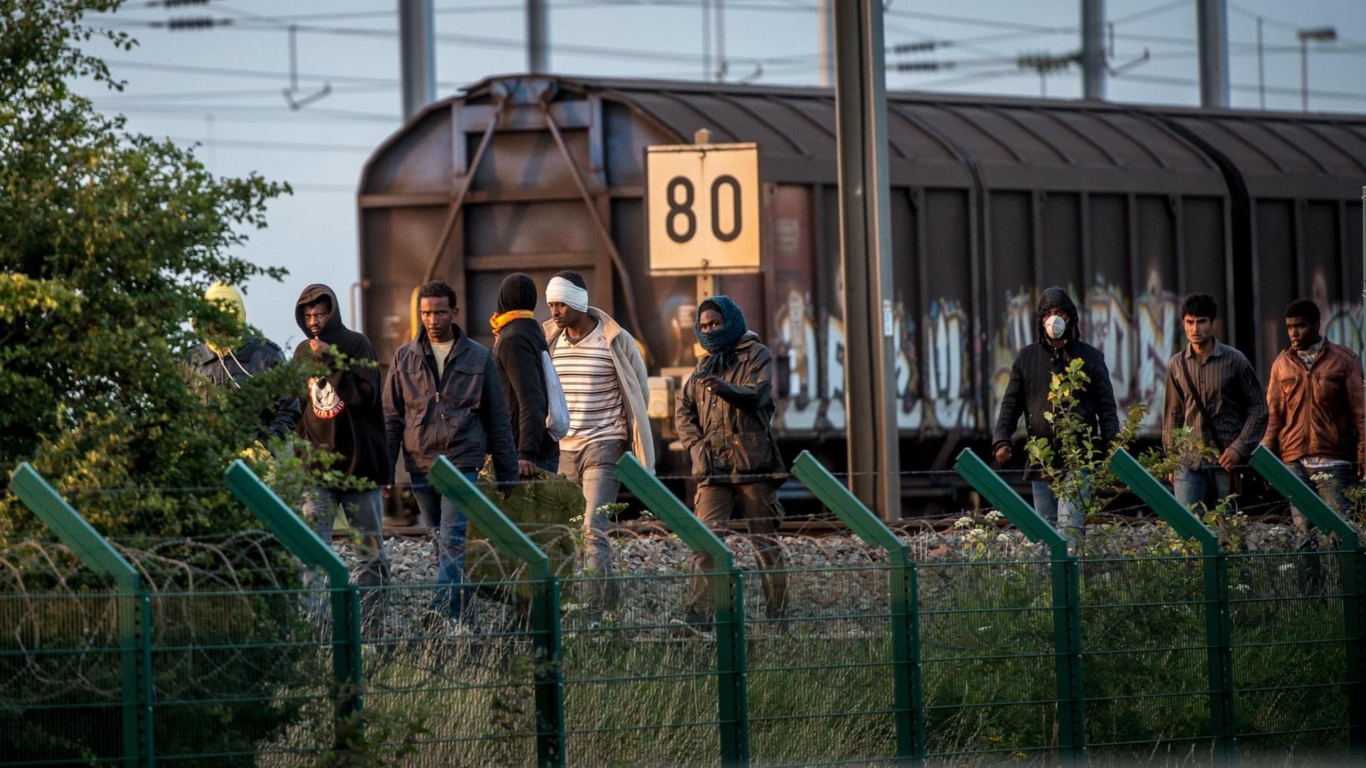 Migrants who successfully crossed the Eurotunnel terminal walk on the side of the railroad as they try to reach a shuttle to Great Britain Migrants who successfully crossed the Eurotunnel terminal walk on the side of the railroad as they try to reach a shuttle to Great Britain