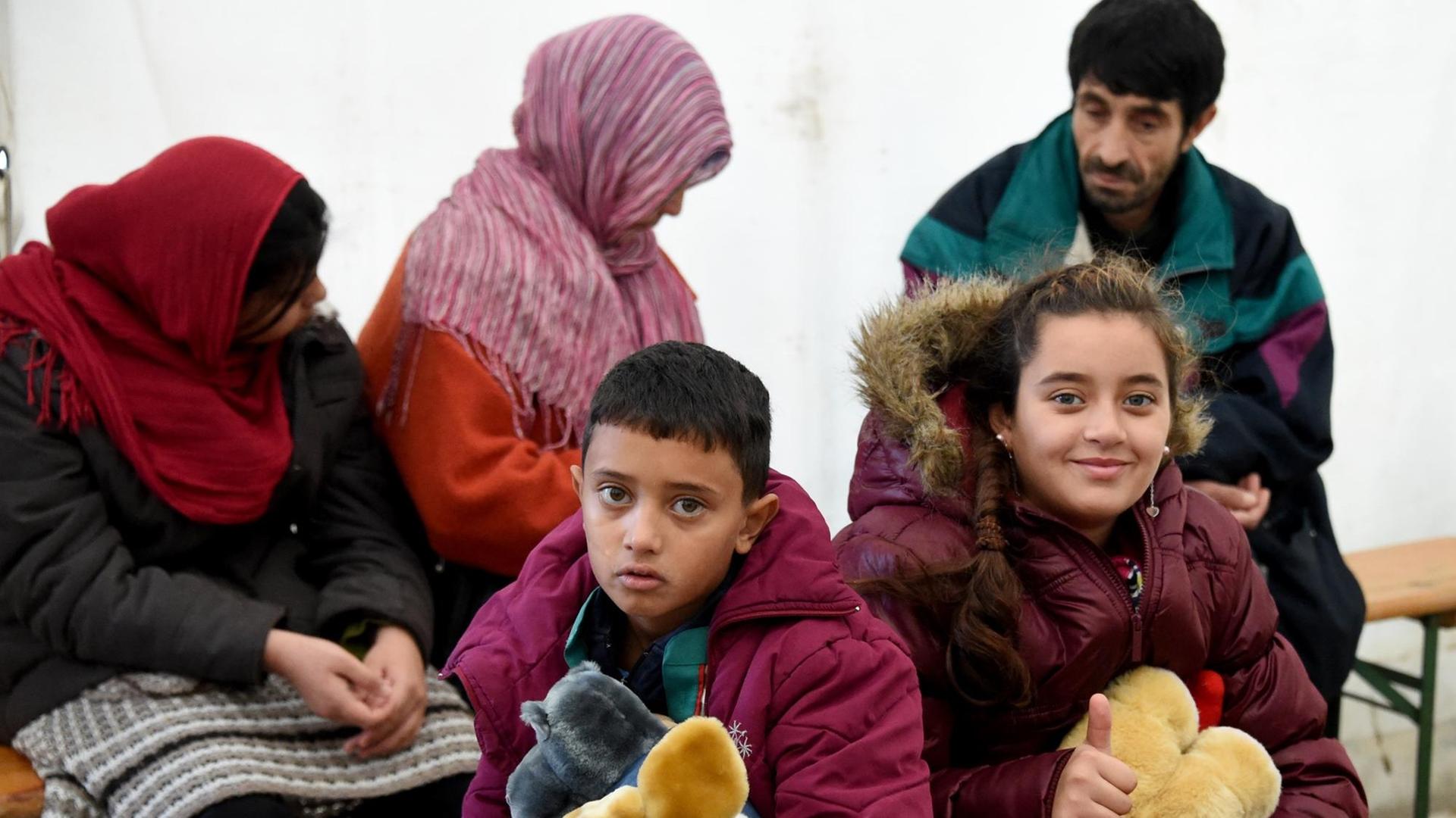 Die aus Syrien stammenden Geschwister Mohammed und Sedra sitzen am 17.11.2015 auf dem Gelände der Erstaufnahmeeinrichtung in Neumünster (Schleswig-Holstein) im Wartebereich zur medizinischen Untersuchung. In der größten Erstaufnahmeeinrichtung des Landes mit zuletzt 4700 Flüchtlingen hat das Universitätsklinikum Schleswig-Holstein (UKSH) in Containern und Zelten zwei parallele Untersuchungsbereiche aufgebaut und eine Röntgen-Anlage. Dort wird die vorgeschriebene medizinische Erstuntersuchung bei jedem Flüchtling vorgenommen. Die aus Syrien stammenden Geschwister Mohammed und Sedra sitzen am 17.11.2015 auf dem Gelände der Erstaufnahmeeinrichtung in Neumünster (Schleswig-Holstein) im Wartebereich zur medizinischen Untersuchung. In der größten Erstaufnahmeeinrichtung des Landes mit zuletzt 4700 Flüchtlingen hat das Universitätsklinikum Schleswig-Holstein (UKSH) in Containern und Zelten zwei parallele Untersuchungsbereiche aufgebaut und eine Röntgen-Anlage. Dort wird die vorgeschriebene medizinische Erstuntersuchung bei jedem Flüchtling vorgenommen.