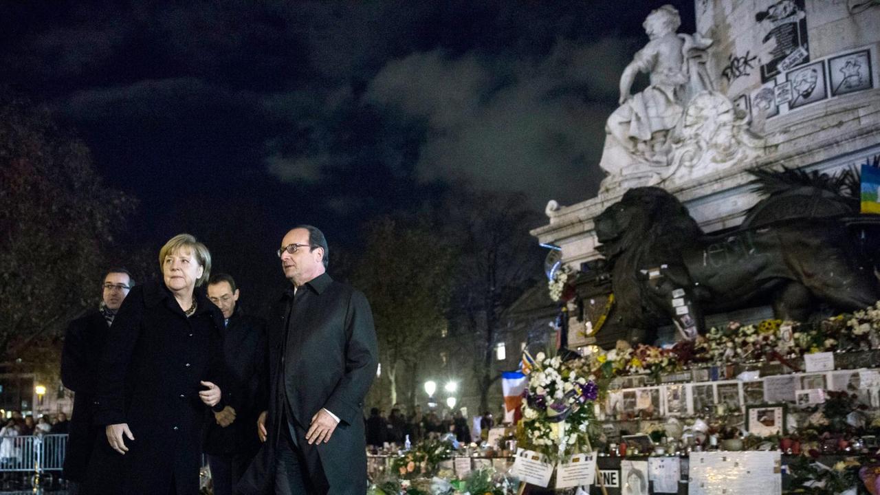 Bundeskanzlerin Merkel und Frankreichs Präsident Hollande auf der Place de la République in Paris, es ist dunkel, beide tragen Mäntel. Bundeskanzlerin Merkel und Frankreichs Präsident Hollande auf der Place de la République in Paris, es ist dunkel, beide tragen Mäntel.