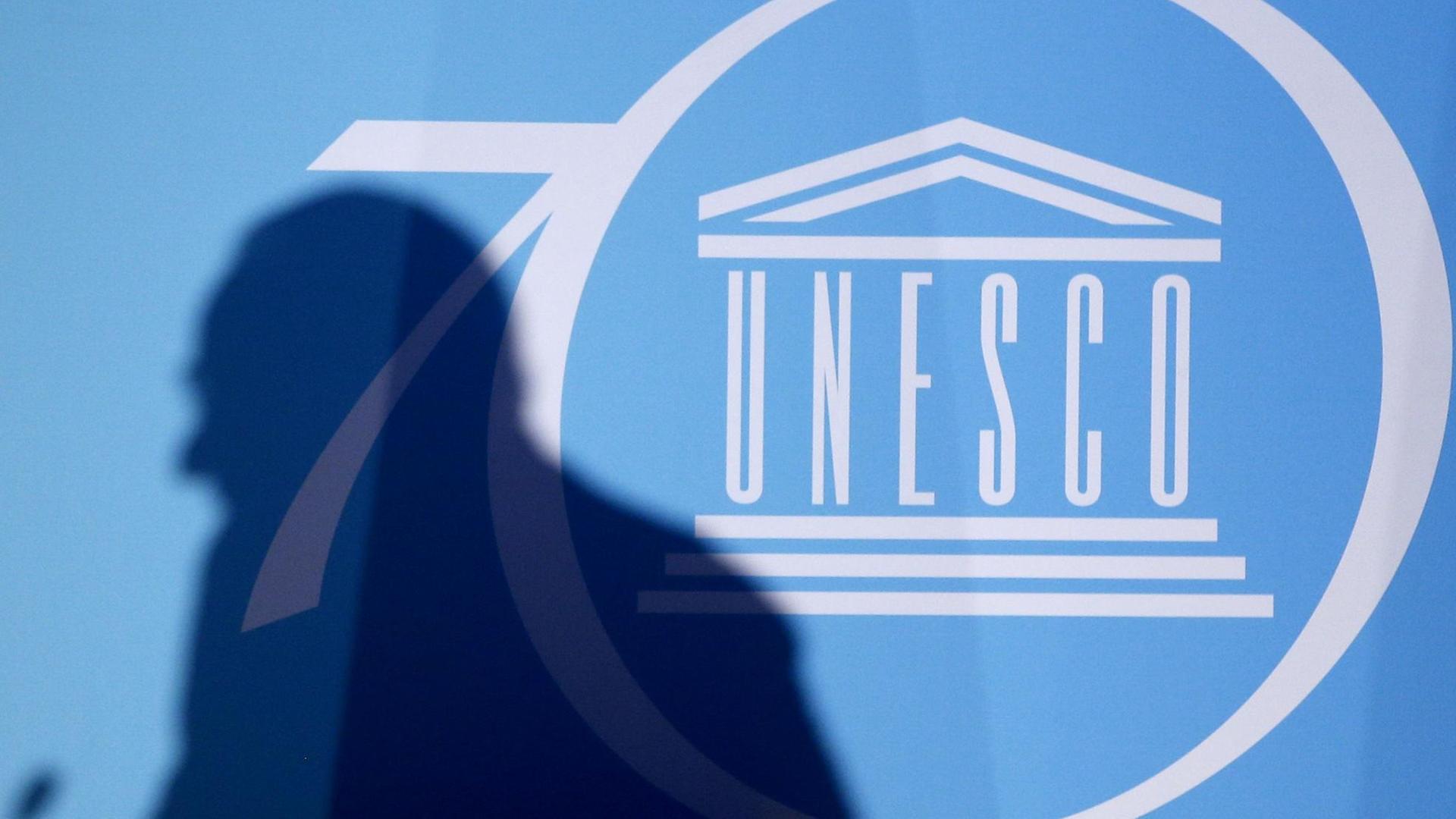 Der Schatten eines Mannes ist vor dem Logo der UNO-Kulturorganisation UNESCO zu sehen, Der Schatten eines Mannes ist vor dem Logo der UNO-Kulturorganisation UNESCO zu sehen,