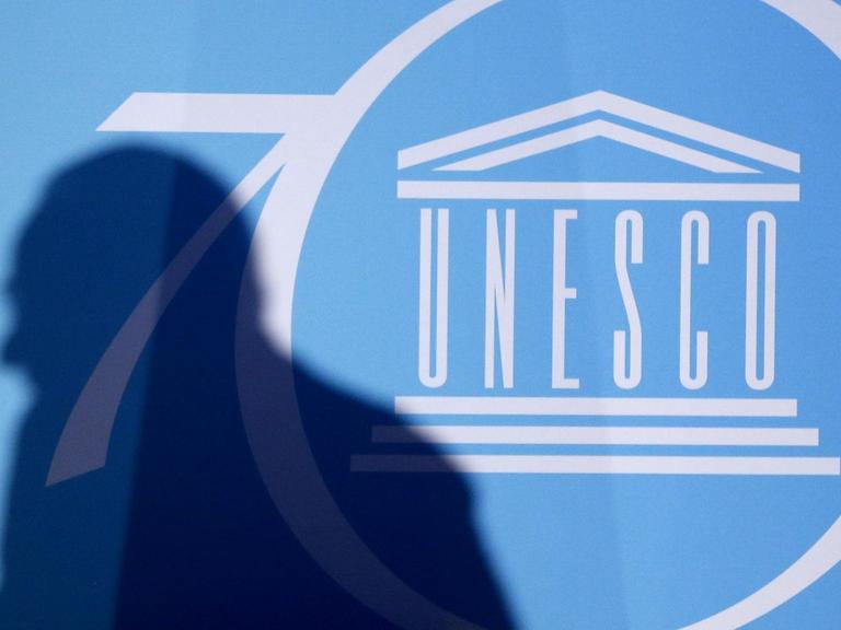 Der Schatten eines Mannes ist vor dem Logo der UNO-Kulturorganisation UNESCO zu sehen,