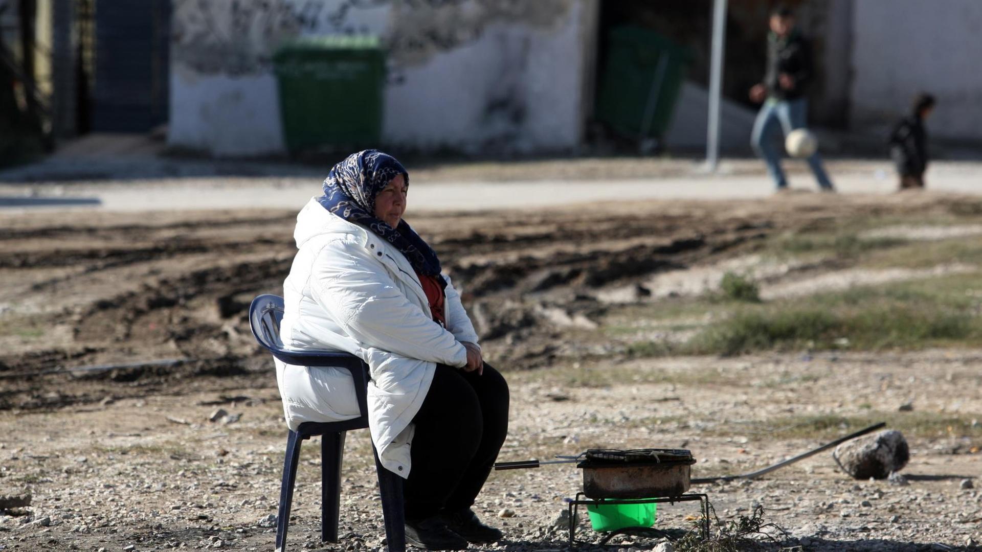 Eine Frau sitzt an einem Camping-Kocher in einem Flüchtlingslager in Thessaloniki, Griechenland.