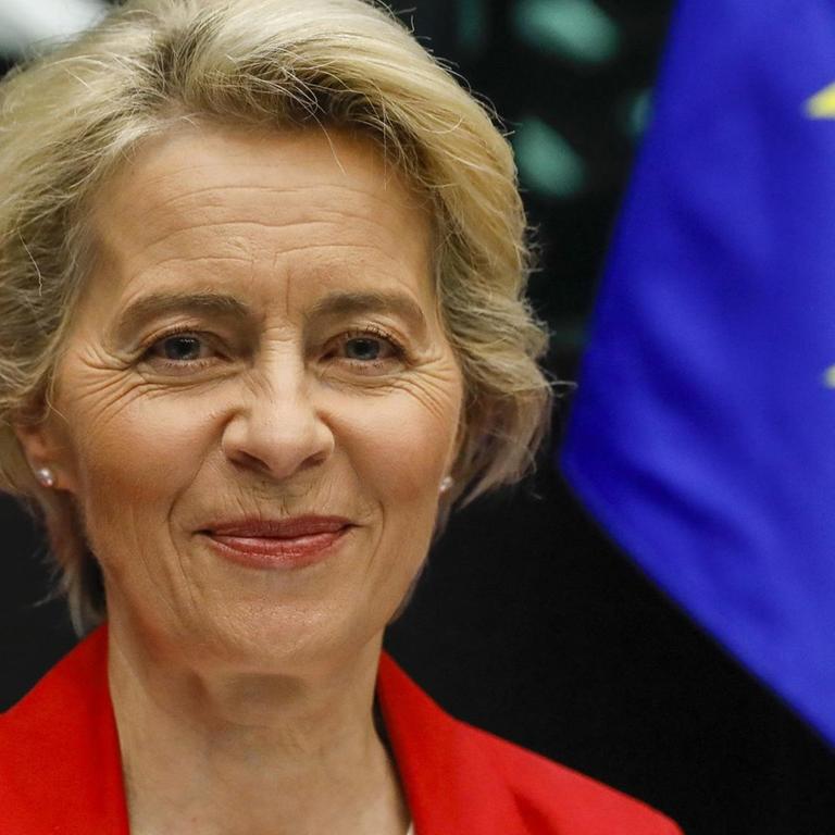 Porträtbild von EU-Kommissionspräsidentin Ursula von der Leyen neben einer EU-Flagge