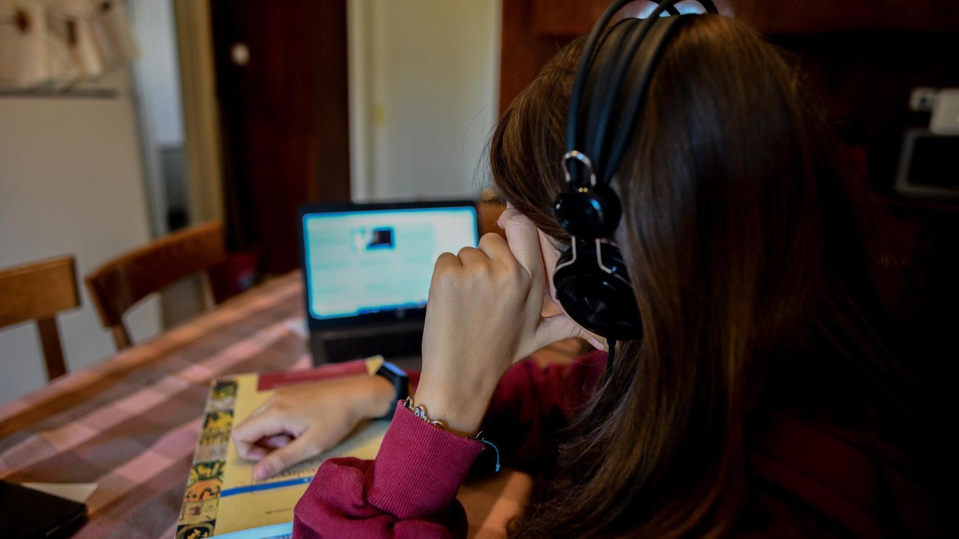 Das Bild zeigt eine Schülerin beim Online-Unterricht vor einem Laptop am Küchentisch. Das Bild zeigt eine Schülerin beim Online-Unterricht vor einem Laptop am Küchentisch.