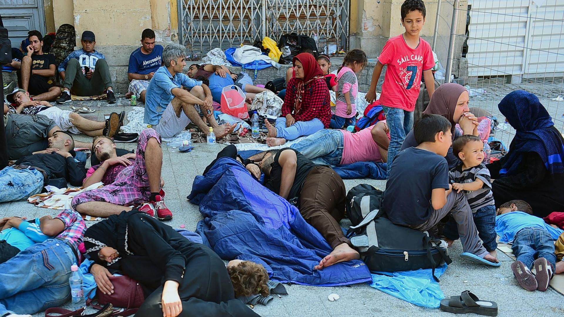 Erschöpfte Flüchtlinge sitzen und liegen vor dem Ostbahnhof in Budapest. Erschöpfte Flüchtlinge sitzen und liegen vor dem Ostbahnhof in Budapest.