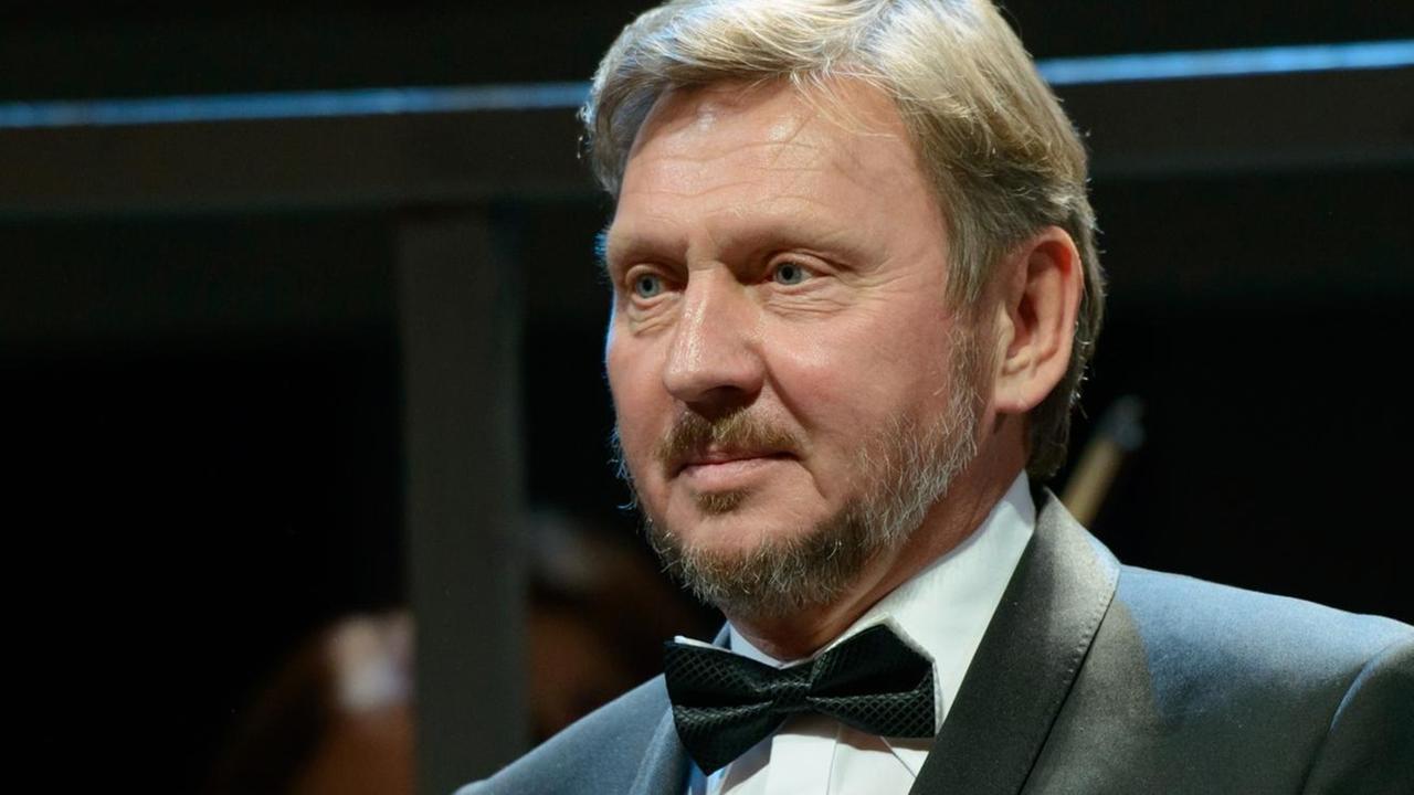 Ein Mann mit blondem Haar und Fliege mit Frack steht auf einer Bühne. Ein Mann mit blondem Haar und Fliege mit Frack steht auf einer Bühne.