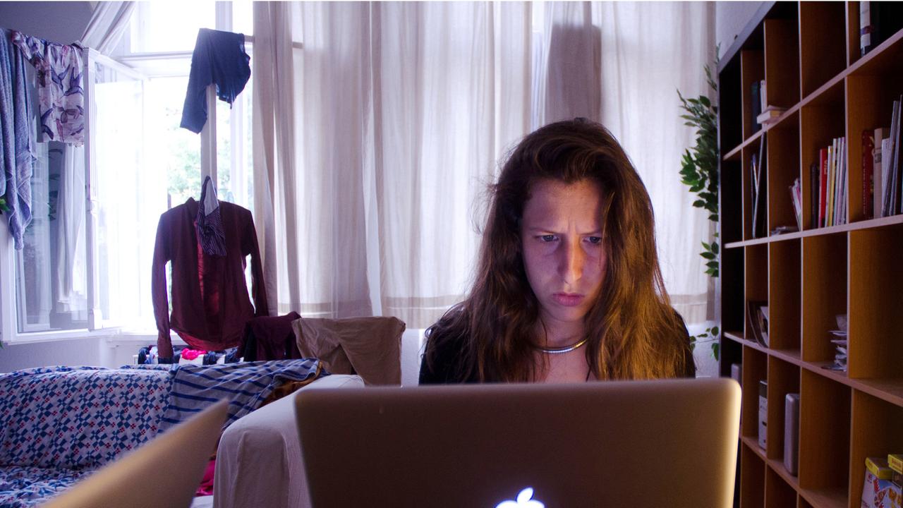 Eine junge Frau sitzt im Homeoffice an ihrem Laptop.