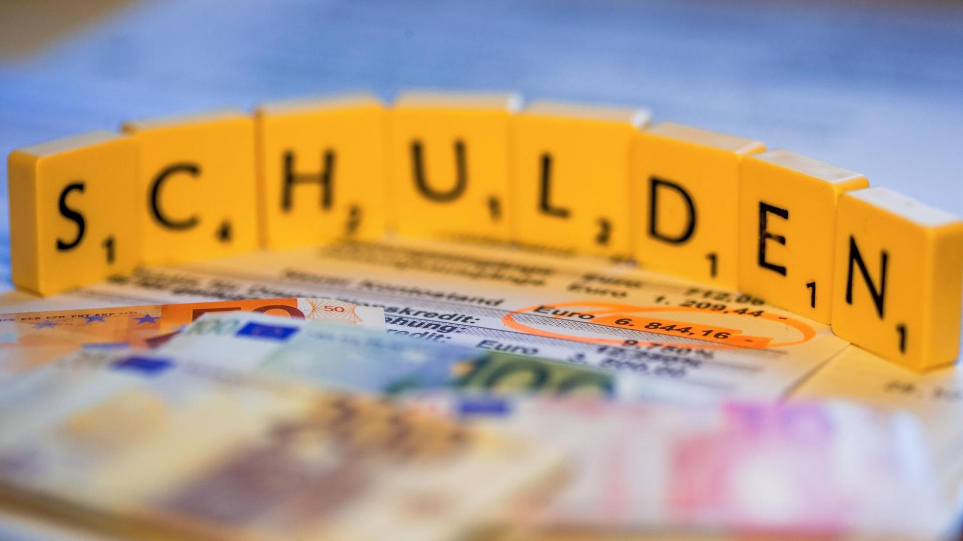 Das Bild zeigt den Schriftzug "Schulden", gebaut aus Scrabblesteinen. Das Bild zeigt den Schriftzug "Schulden", gebaut aus Scrabblesteinen.