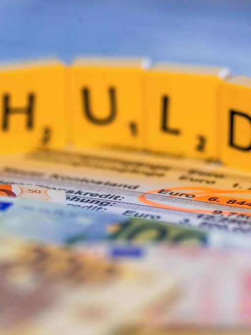 Das Bild zeigt den Schriftzug "Schulden", gebaut aus Scrabblesteinen.