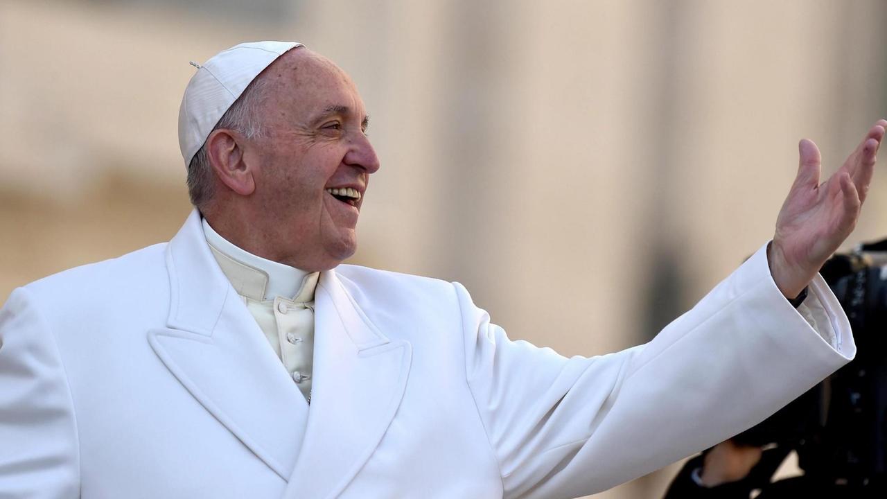 Papst Franziskus lacht und hält den linken Arm in die Luft. Papst Franziskus lacht und hält den linken Arm in die Luft.