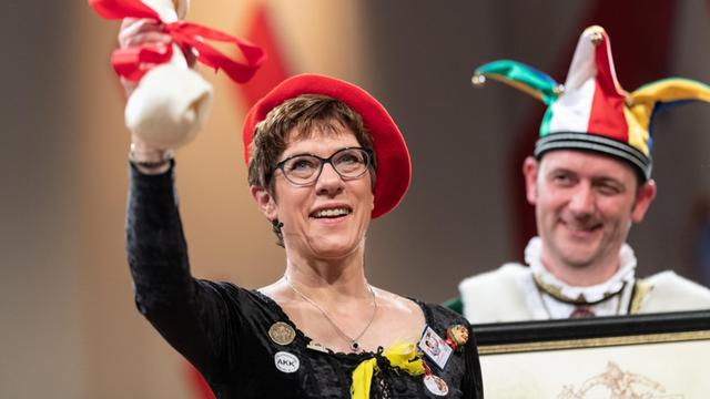 Die Bundesvorsitzende der CDU, Annegret Kramp-Karrenbauer, steht vor dem Narrengericht und hält einen Plastikknochen in der Hand.