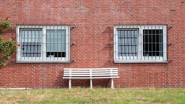 Eine Sitzbank steht vor vergitterten Fenstern in der Unterbringungseinrichtung für Ausreisepflichtige (UfA) der Bezirksregierung Detmold in Büren in Nordrhein-Westfalen