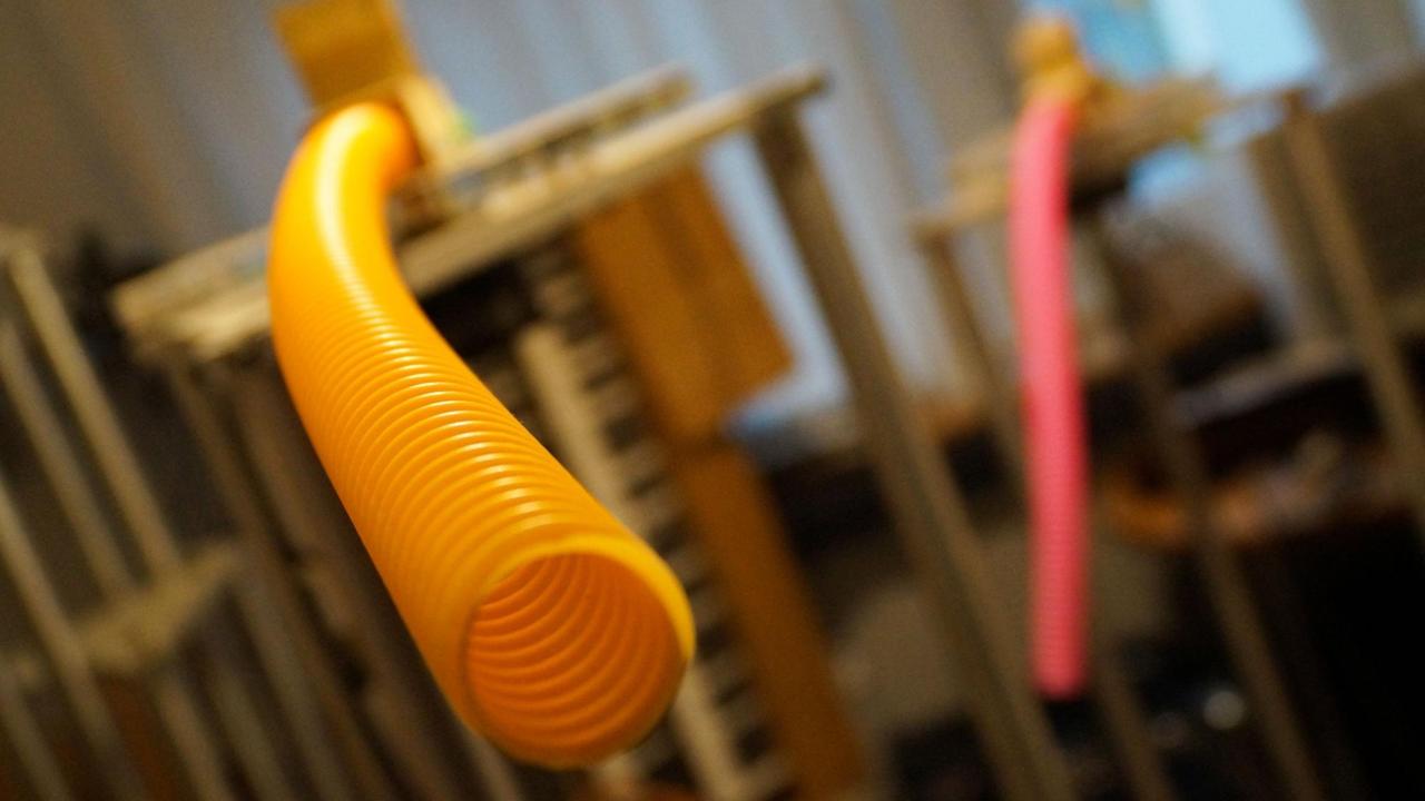 Ein gelber gerippter Schlauch ragt in den Raum hinein. Er ist an einem Motor befestigt, der den Schlauch im Kreis herumwirbeln kann. Ein gelber gerippter Schlauch ragt in den Raum hinein. Er ist an einem Motor befestigt, der den Schlauch im Kreis herumwirbeln kann.