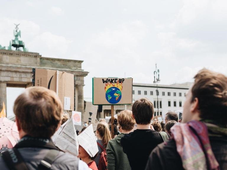 Junge Menschen protestieren am Brandenburger Tor in Berlin gegen die Erderwärmung, auf einem Schild steht "Wake up / Wacht auf".