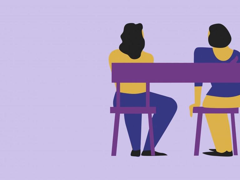 Eine Stuhllehne bildet die Form eines Armes um zwei nebeneinander sitzende Frauen.