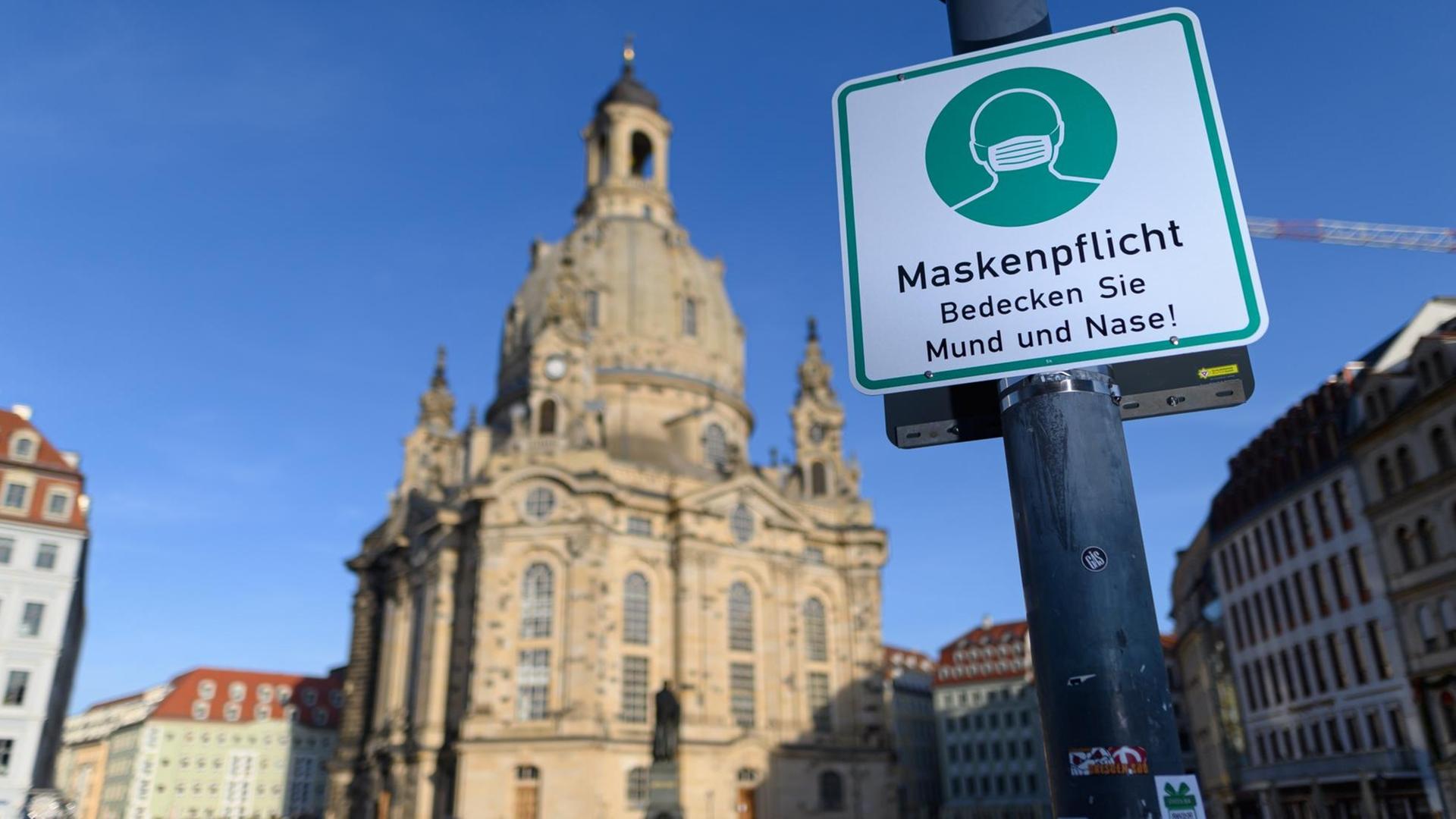 Vor der Frauen-Kirche in Dresden hängt an einer Laterne ein Hinweis-Schild zur Masken-Pflicht. Vor der Frauen-Kirche in Dresden hängt an einer Laterne ein Hinweis-Schild zur Masken-Pflicht.