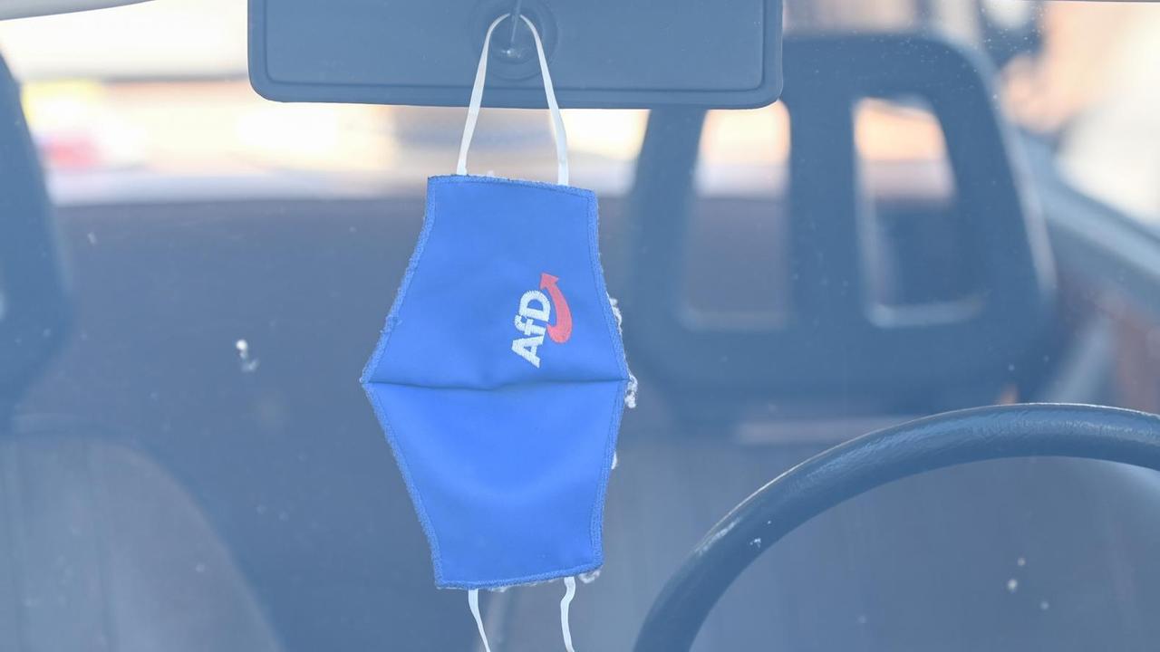 Eine Mund-Nasen-Bedeckung mit dem Logo der AfD hängt am Rande einer Wahlkampfveranstaltung am Rückspiegel eines Trabants. Eine Mund-Nasen-Bedeckung mit dem Logo der AfD hängt am Rande einer Wahlkampfveranstaltung am Rückspiegel eines Trabants.