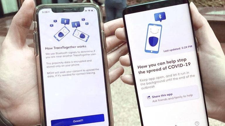 Zwei Smartphones werden nebeneinander gehalten, auf den Displays ist die Corona-App aus Singapur zu sehen. Zwei Smartphones werden nebeneinander gehalten, auf den Displays ist die Corona-App aus Singapur zu sehen.